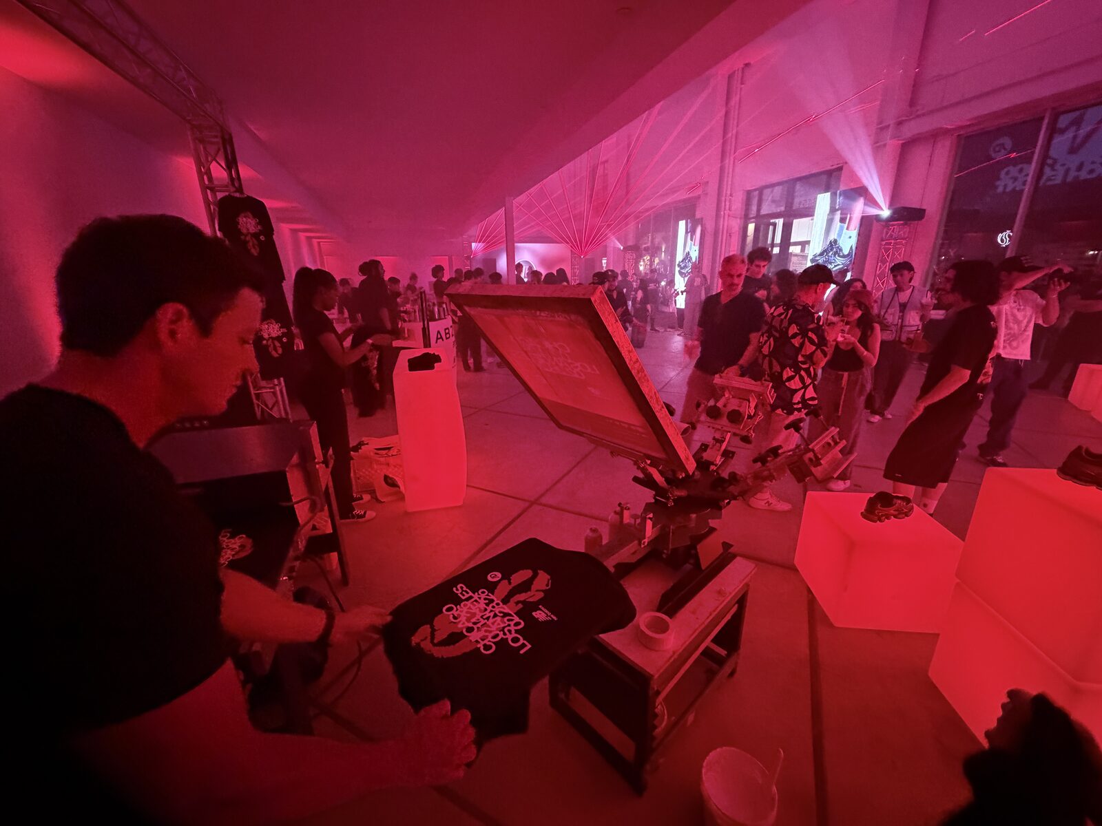 Live screen printing station running at a packed party under red lights