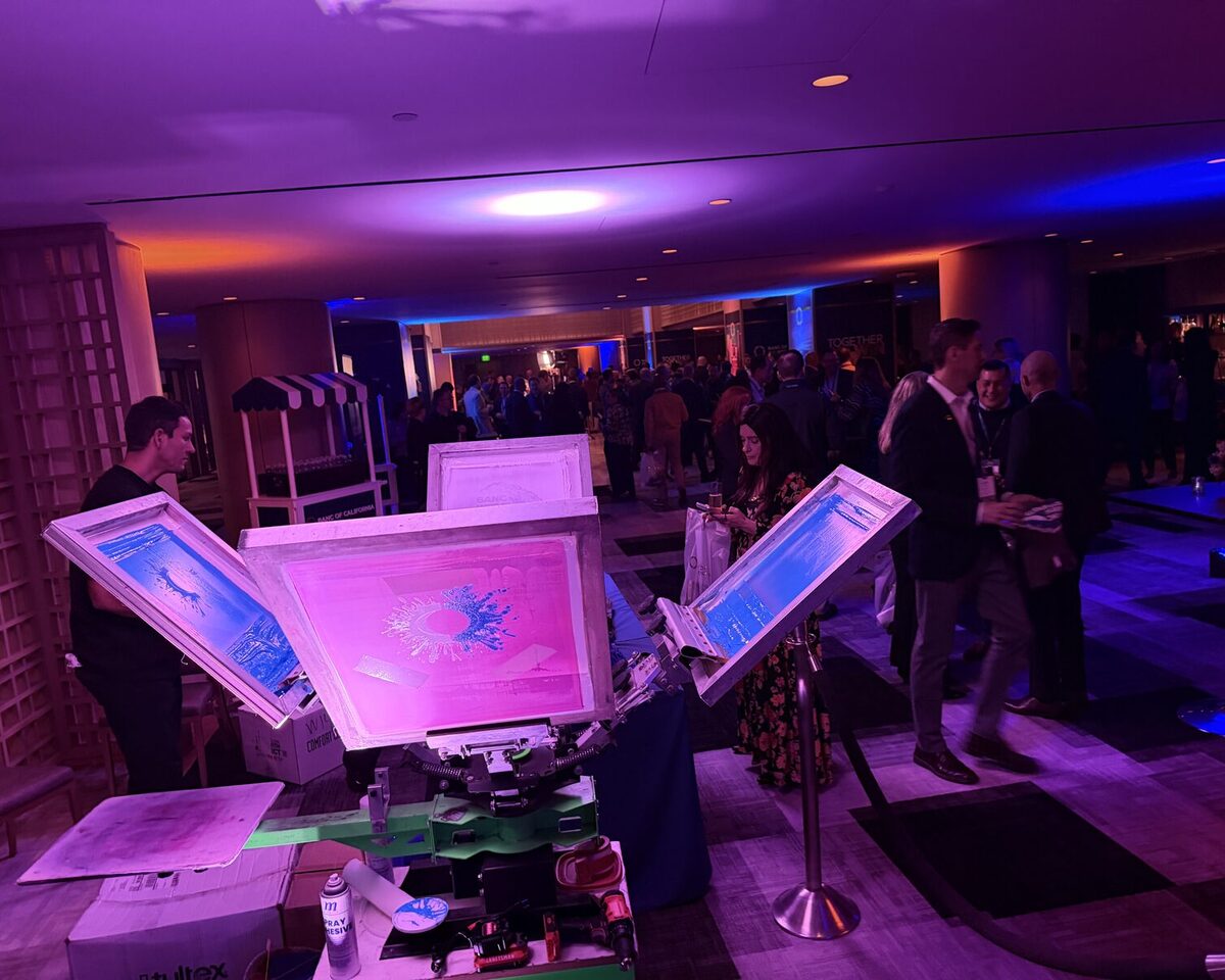 Print screens glowing under purple party lighting with the crowd mingling behind