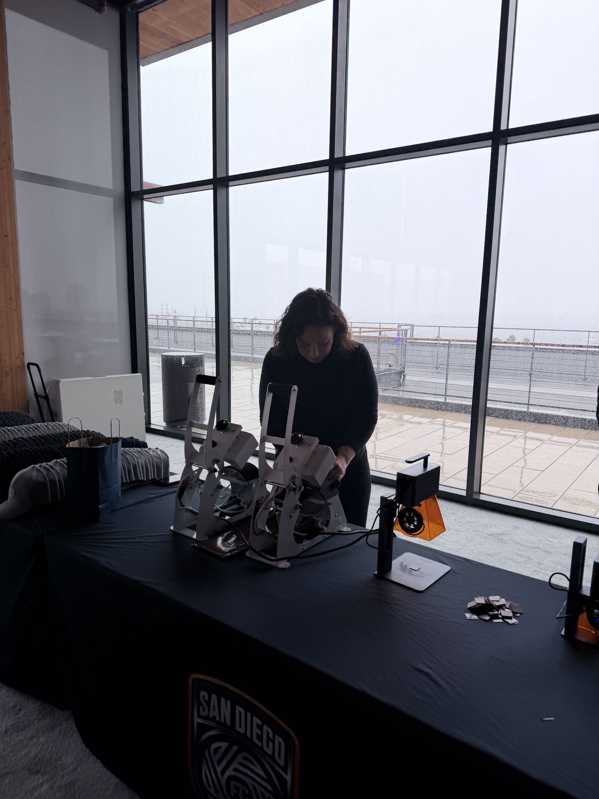 Compact heat press and engraving rig staged on a table by tall windows before guests arrive